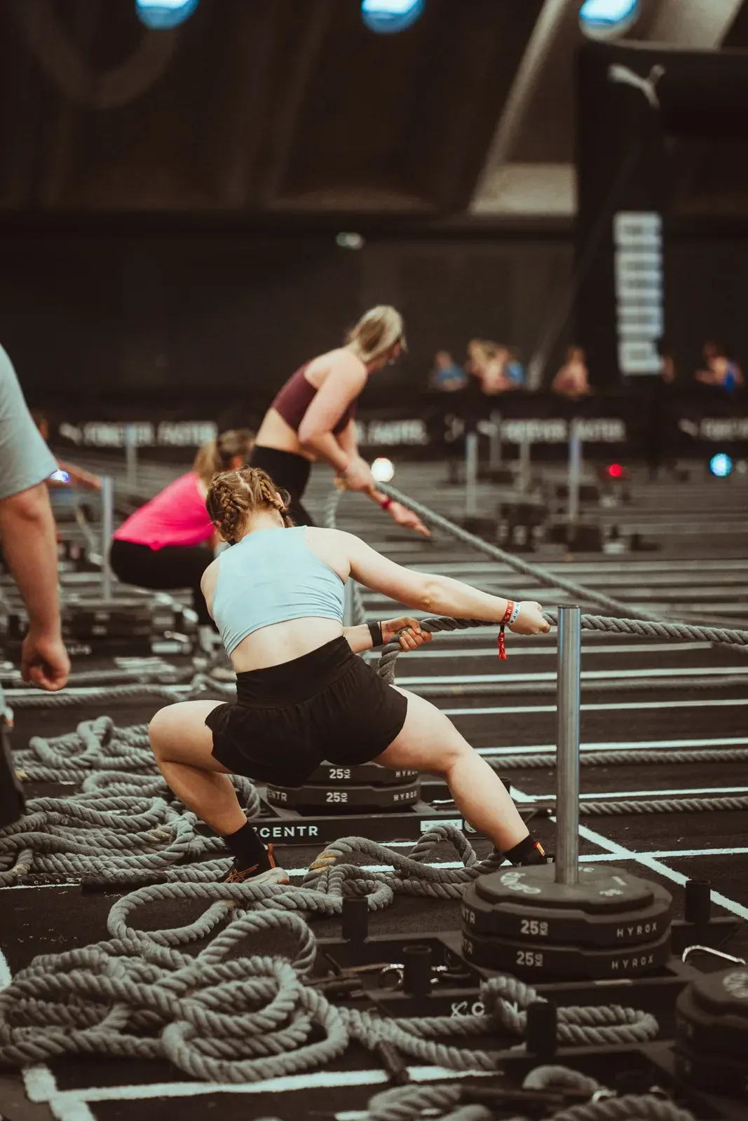 Athlète en fente qui tire la corde à la station Sled Pull, la corde enroulée au sol